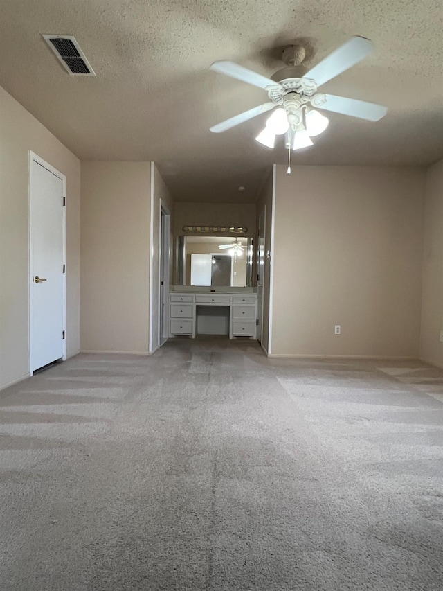 unfurnished living room with ceiling fan, light carpet, and a textured ceiling