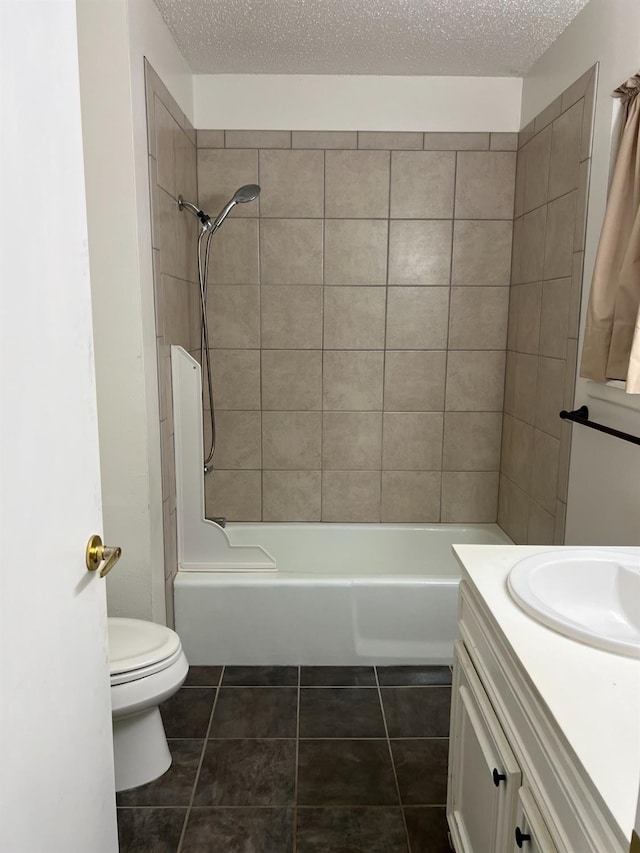 full bathroom with tile patterned flooring, tiled shower / bath, toilet, and a textured ceiling