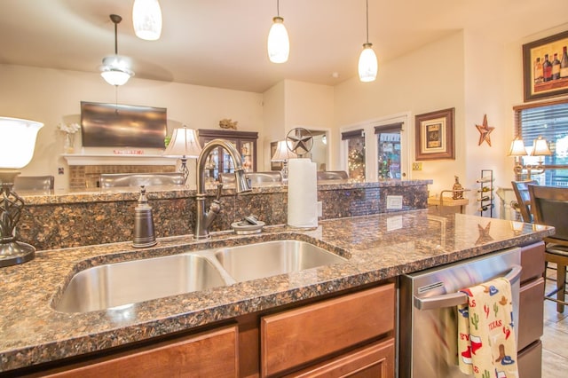 kitchen featuring sink, dark stone counters, hanging light fixtures, and dishwasher