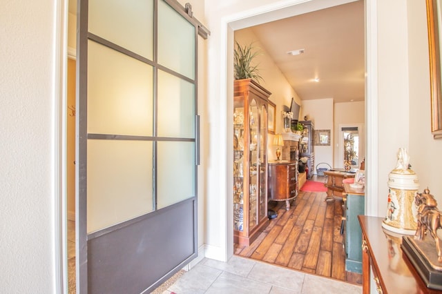 hall with a barn door and light tile patterned floors