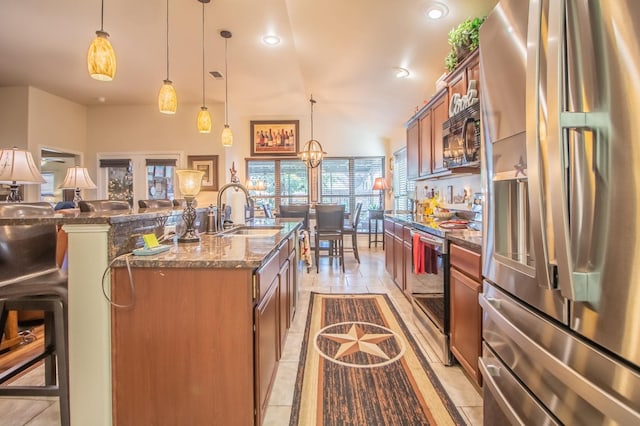 kitchen with pendant lighting, sink, a breakfast bar area, stainless steel appliances, and a center island with sink