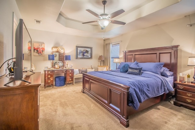 bedroom with ceiling fan, a raised ceiling, and light colored carpet