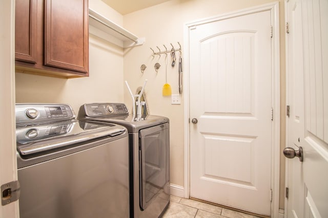 laundry room with cabinets, light tile patterned floors, and independent washer and dryer