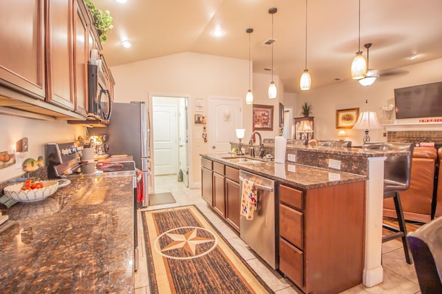 kitchen with sink, a breakfast bar area, vaulted ceiling, hanging light fixtures, and appliances with stainless steel finishes