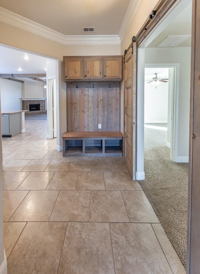 mudroom with crown molding, light colored carpet, a barn door, and ceiling fan