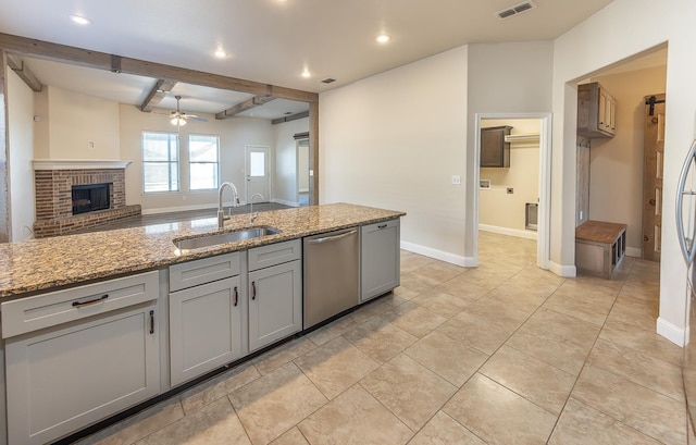 kitchen with sink, dishwasher, gray cabinetry, light stone counters, and beamed ceiling