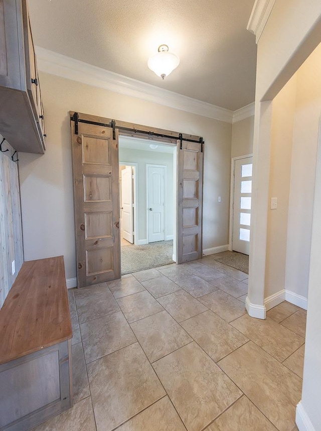 foyer featuring light tile patterned floors, ornamental molding, and a barn door