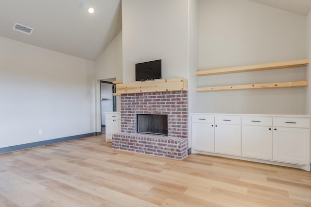 unfurnished living room with a brick fireplace, light hardwood / wood-style floors, and high vaulted ceiling