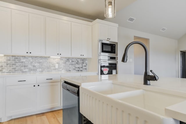 kitchen with stainless steel appliances, sink, white cabinets, and decorative light fixtures