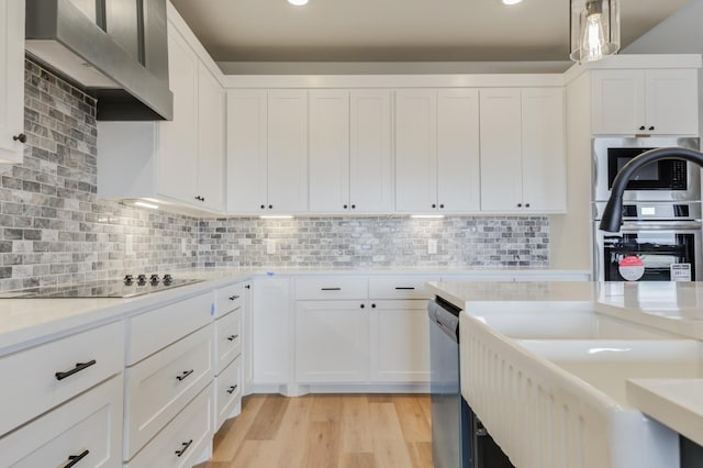 kitchen featuring white cabinetry, pendant lighting, and wall chimney exhaust hood