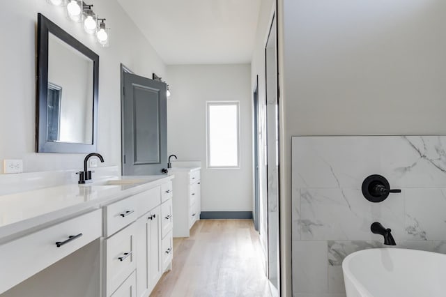 bathroom featuring hardwood / wood-style flooring, vanity, and a bath