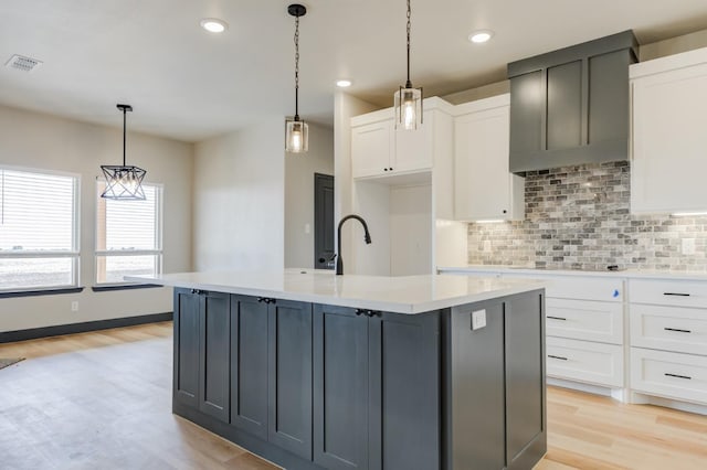 kitchen featuring pendant lighting, white cabinetry, and an island with sink