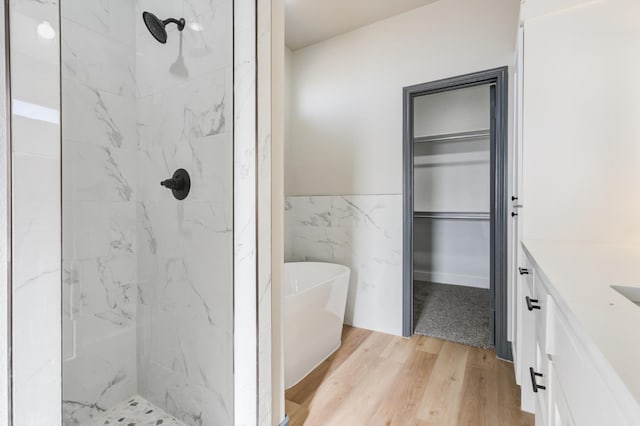 bathroom with tile walls, vanity, hardwood / wood-style flooring, and shower with separate bathtub