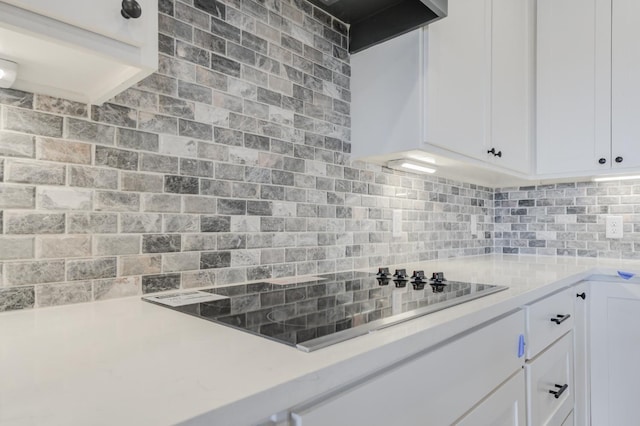 kitchen with white cabinetry, black electric stovetop, and tasteful backsplash