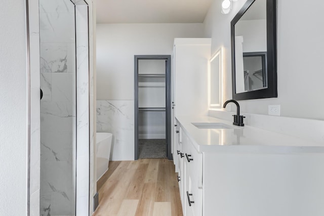 bathroom featuring wood-type flooring, a washtub, tile walls, and vanity