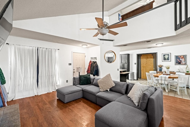 living room with ceiling fan, wood-type flooring, and high vaulted ceiling