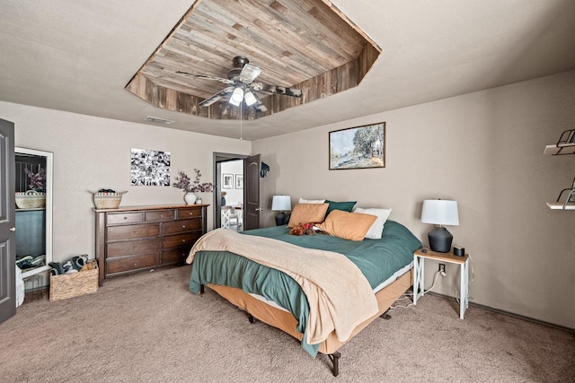 bedroom with a raised ceiling, carpet floors, and ceiling fan