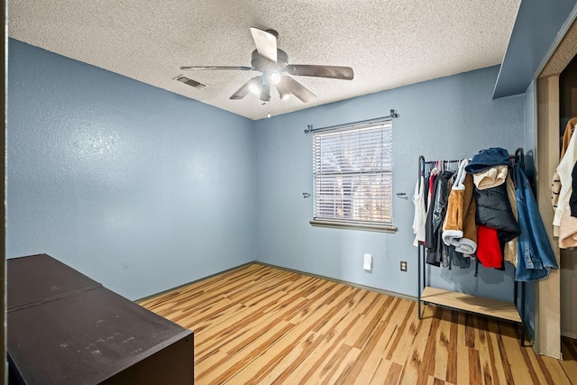 home office with a textured ceiling, wood-type flooring, and ceiling fan