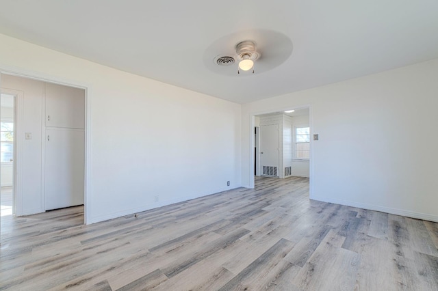 spare room with ceiling fan, a healthy amount of sunlight, and light hardwood / wood-style flooring