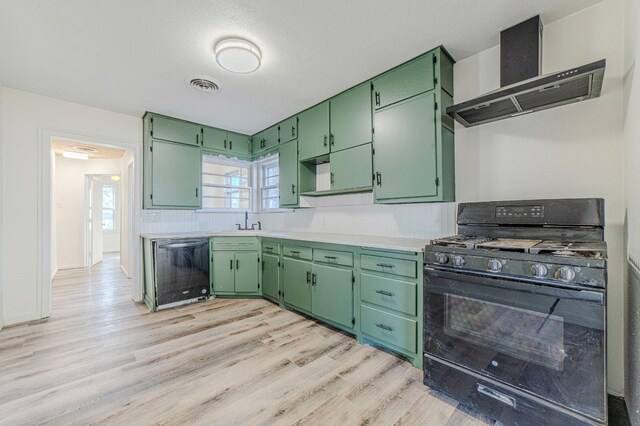 kitchen with green cabinets, dishwasher, black gas range, and wall chimney range hood