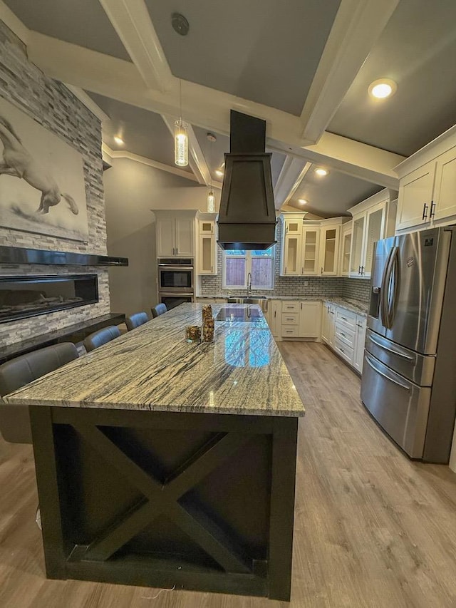 kitchen with white cabinetry, a spacious island, appliances with stainless steel finishes, and a breakfast bar