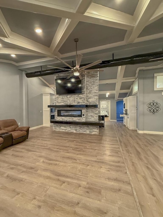 living room with coffered ceiling, beam ceiling, ceiling fan, a fireplace, and light hardwood / wood-style floors