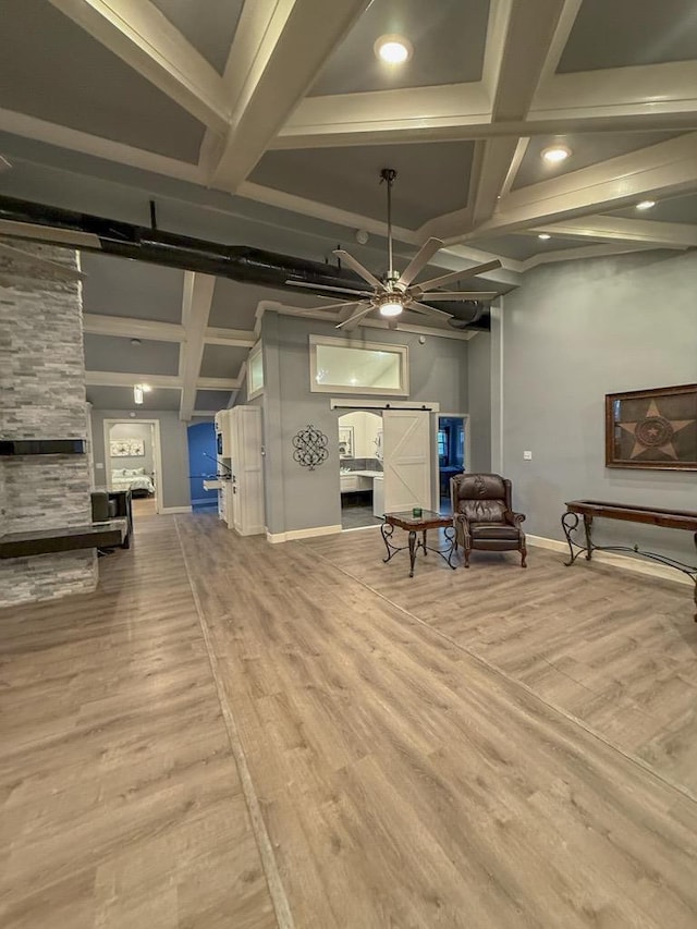 interior space with hardwood / wood-style flooring, ceiling fan, beam ceiling, coffered ceiling, and a barn door