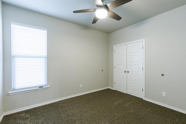 unfurnished bedroom featuring ceiling fan, dark carpet, and a closet