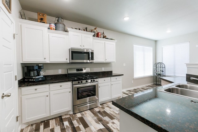 kitchen featuring appliances with stainless steel finishes, sink, white cabinets, and light hardwood / wood-style floors