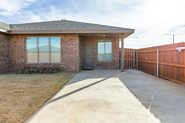 view of exterior entry with a yard and a patio area