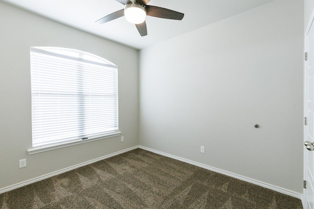 spare room with dark carpet and ceiling fan