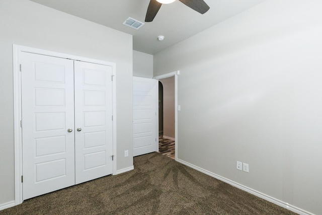 unfurnished bedroom featuring ceiling fan, dark carpet, and a closet