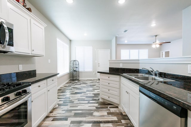 kitchen featuring stainless steel appliances, white cabinetry, plenty of natural light, and sink