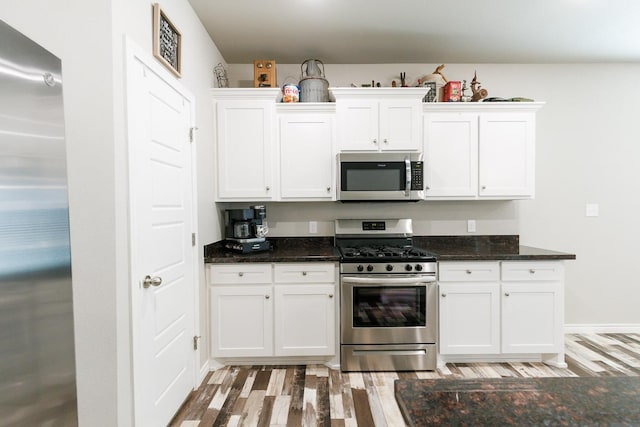 kitchen featuring dark stone countertops, appliances with stainless steel finishes, and white cabinets