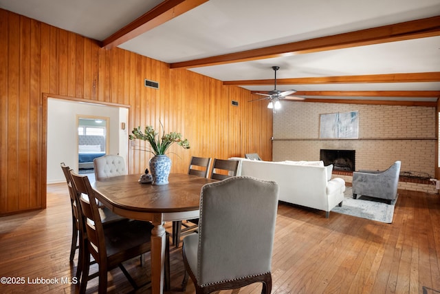 2005 32nd St, Lubbock, TX 79411 - dining room with beam ceiling, hardwood / wood-style flooring, a ceiling fan, wood walls, and a fireplace