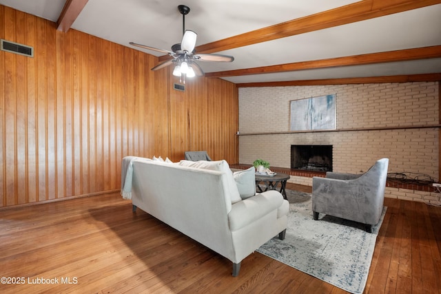 2005 32nd St, Lubbock, TX 79411 - living room featuring beamed ceiling, a ceiling fan, wooden walls, wood-type flooring, and a fireplace