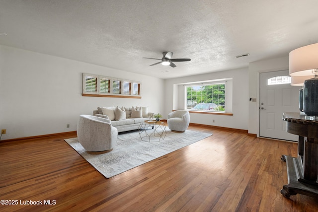 2005 32nd St, Lubbock, TX 79411 - living room with ceiling fan, baseboards, wood finished floors, a textured ceiling, and a wood stove