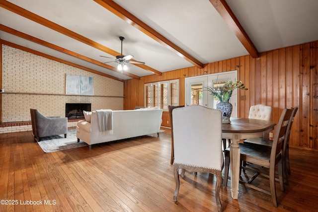 2005 32nd St, Lubbock, TX 79411 - dining area featuring brick wall, hardwood / wood-style floors, ceiling fan, wooden walls, and a brick fireplace