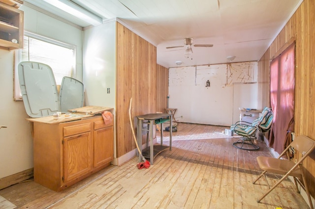 interior space with ceiling fan, ornamental molding, wooden walls, and light hardwood / wood-style floors