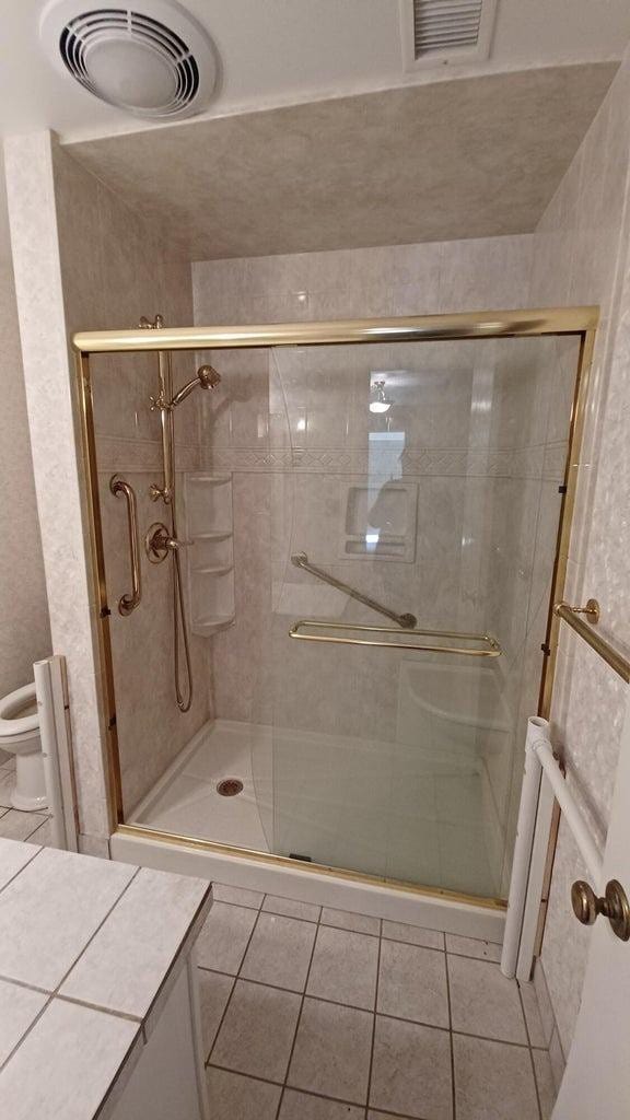 bathroom featuring an enclosed shower, tile patterned floors, and toilet