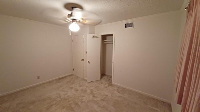 unfurnished bedroom featuring ornamental molding, light colored carpet, ceiling fan, a textured ceiling, and a closet