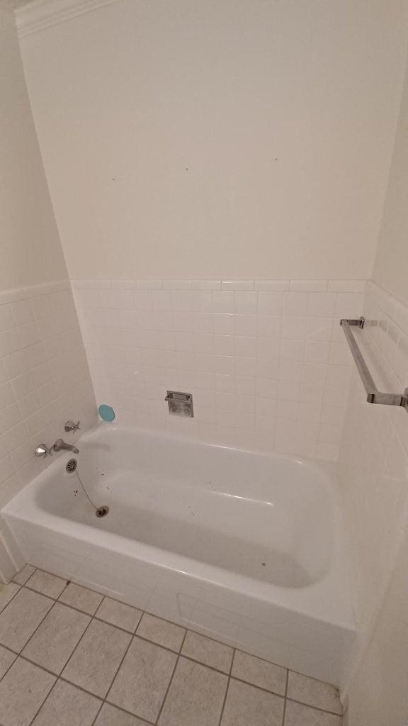 bathroom with tile patterned floors and a bath