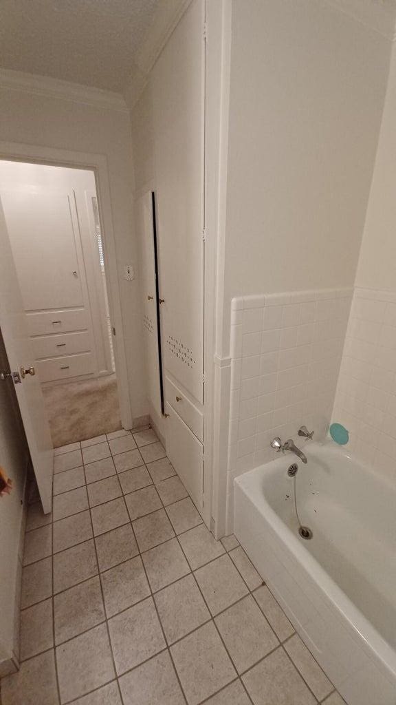 bathroom featuring tile patterned flooring, crown molding, and a washtub