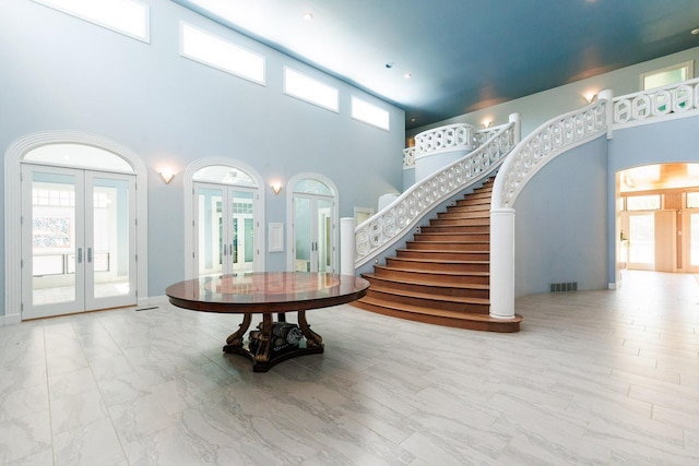 entryway with french doors, a towering ceiling, and plenty of natural light