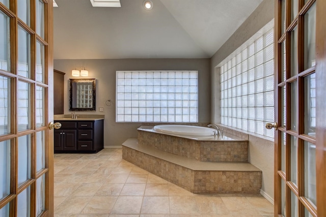 bathroom with french doors, vaulted ceiling, vanity, tiled tub, and tile patterned flooring