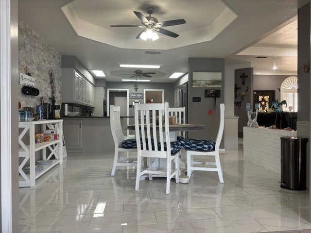 dining area featuring a raised ceiling and ceiling fan