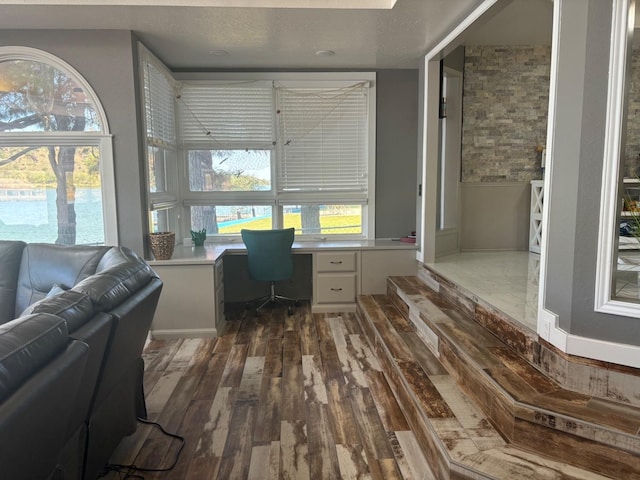 home office with dark wood-type flooring, built in desk, a textured ceiling, and plenty of natural light