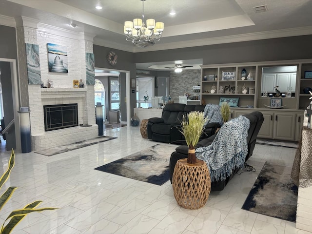 living room featuring crown molding, a fireplace, a raised ceiling, and ceiling fan with notable chandelier