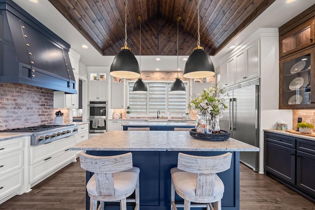 7733 46th St, Lubbock, TX 79407 - kitchen with stainless steel appliances, wooden ceiling, decorative backsplash, a kitchen island, and a breakfast bar