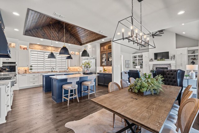 7733 46th St, Lubbock, TX 79407 - dining space with lofted ceiling, a fireplace, dark wood finished floors, wood ceiling, and recessed lighting